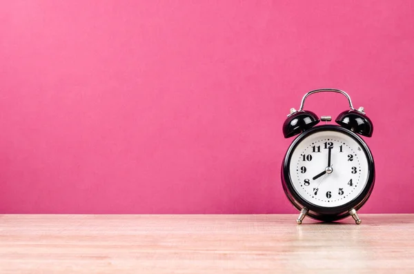 木製ワークベンチのレトロ目覚まし時計ピンク色の背景 — ストック写真
