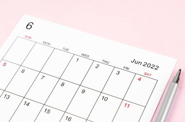 Haziran 2022 takvim kağıdını pembe arka planda kalemle kapat.