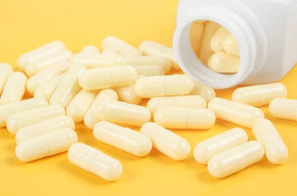 Żółte Kapsułki Farmaceutyczne Żółtym Tle Biała Butelka Tabletkami Medycznymi — Zdjęcie stockowe