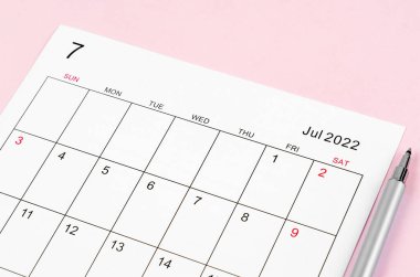 Haziran 2022 takvim kağıdını pembe arka planda kalemle kapat.