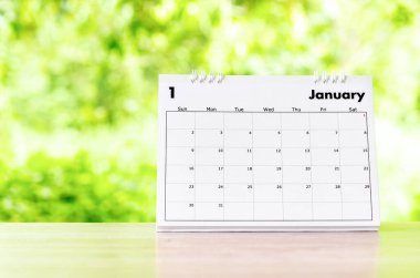 Doğanın arka planındaki ahşap masa üzerinde organizatörün planlaması ve hatırlatması için Ocak 2022 takvim masası.