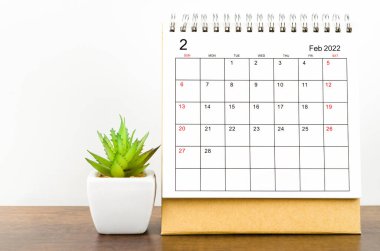 Şubat 2022 masa takvimi. Ahşap masada saksı var..