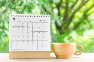 Doğanın arka planındaki ahşap masa üzerinde planlama ve hatırlatma için Ağustos 2022 Takvim Masası.