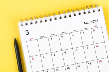 Sarı zemin üzerinde Mart 2022 yakın çekim masa takvimi.