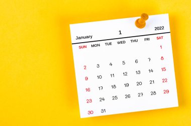 The January 2022 and wooden push pin on yellow background.