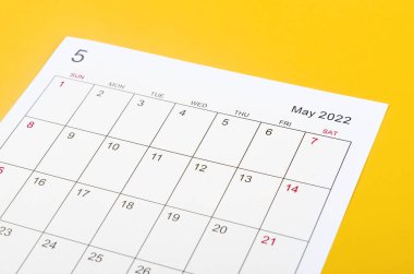 Close up May 2022 calendar sheet on yellow background.