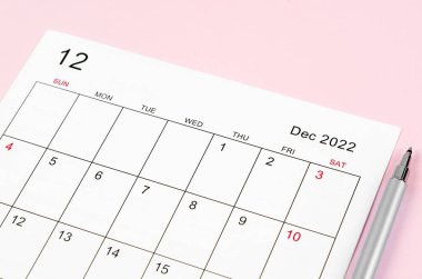 Aralık 2022 takvim kağıdını pembe arka planda kalemle kapat.