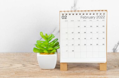 Şubat 2022 masa takvimi. Tahta masa üzerinde bitki var..