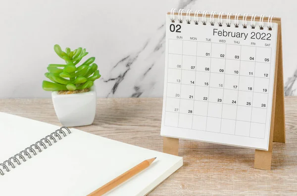 Şubat 2022 masa takvimi. Tahta masa üzerinde bitki var..