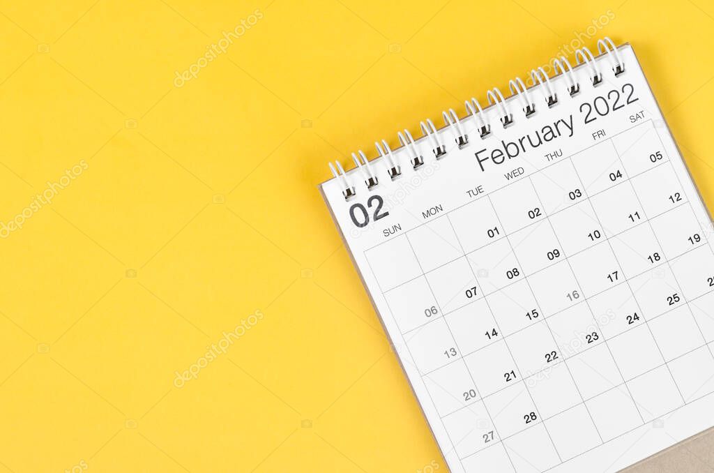 The February 2022 desk calendar on yellow background with empty space.