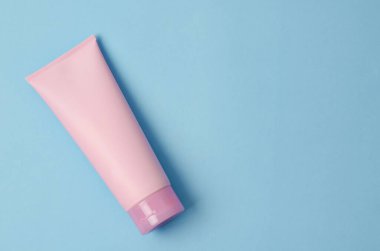 Mavi arkaplana bir kozmetik pembe krem tüpü boşalt..