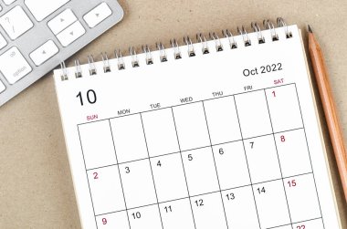 Ekim 2022 masa takvimi. Ahşap arka planda kalem var..
