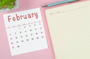 Pembe zemin üzerine not defteriyle Şubat 2022 takvimi.