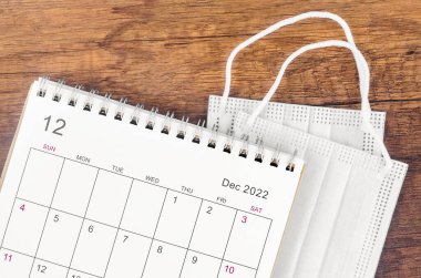 Aralık 2022 Ahşap zemin üzerinde cerrahi maske tıbbi takvimi.