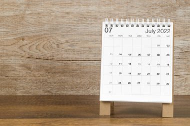 Ahşap zemin üzerinde Temmuz 2022 masa takvimi.