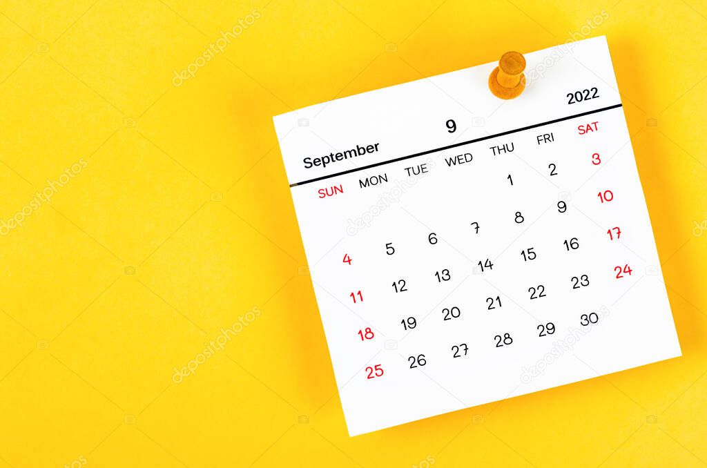 The September 2022 and wooden push pin on yellow background.