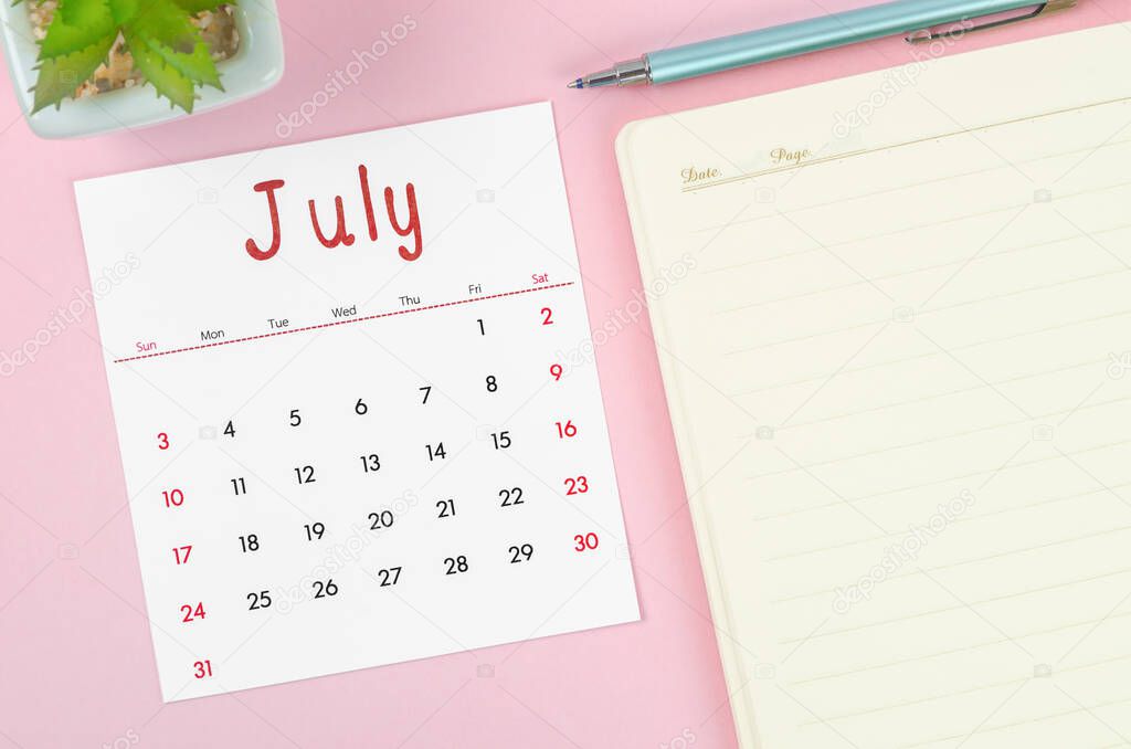 The July 2022 calendar with note book on pink background.