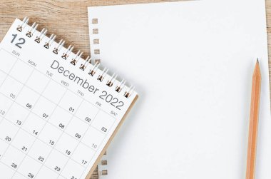 Ahşap zemin üzerinde mesajınız veya mesajınız için boş kağıt sayfa içeren Aralık 2022 masa takvimi.