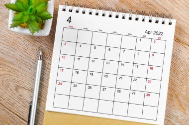 Nisan 2022 masa takvimi ve tahta masa üzerinde kalem..