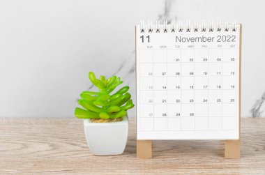 Kasım 2022 masa takvimi. Tahta masa üzerinde bitki var..