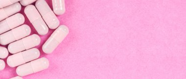 Pembe kapsül hapları pembe arka planda fotokopi alanı ile birlikte. Eczane web pankartı kavramları.