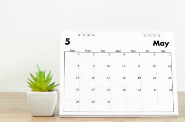 Mayıs 2022 masa takvimi. Tahta masa üzerinde saksı var..
