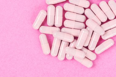 Pembe kapsül hapları pembe arka planda fotokopi alanı ile.
