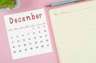 Aralık 2022 takviminde pembe arkaplan üzerine not defteri.