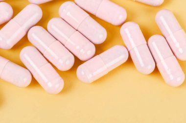 Sarı arka planda pembe kapsül hapları 