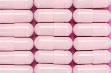 Pembe kapsül hapları pembe arka planda..