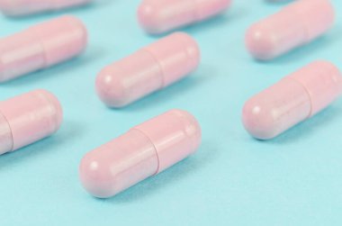 Mavi arka planda Pembe kapsül hapları.