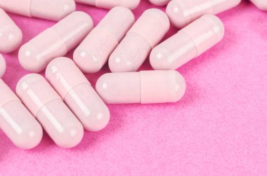 Pembe kapsül hapları pembe arka planda. 