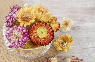 Kurutulmuş saman çiçeğinin başları ahşap arka planda..