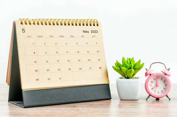 木製のテーブルの上にピンクの目覚まし時計と2022年5月デスクカレンダー — ストック写真