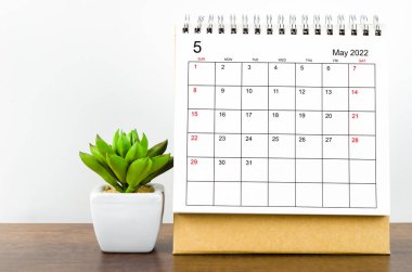 Mayıs 2022 masa takvimi. Tahta masa üzerinde bitki var..