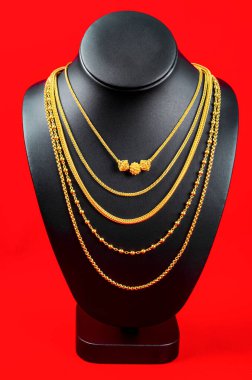 Kolye standı kırmızı kadife kumaşın üzerinde altın kolyeyle