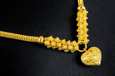 Altın kolye ve kalp şeklinde siyah deri kolye..