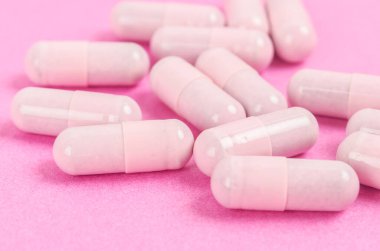 Pembe kapsül hapları pembe arka planda. 
