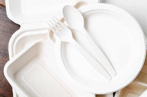 Eco friendly biodegradable paper disposable for packaging food on wooden background.