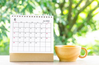 Doğa arka planındaki ahşap masa üzerinde planlama ve hatırlatma için Haziran 2022 Takvim masası.