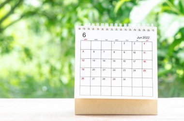 Doğa arka planındaki ahşap masa üzerinde planlama ve hatırlatma için Haziran 2022 Takvim masası.