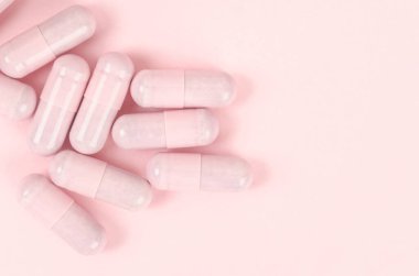Pembe kapsül hapları pembe arka planda. 