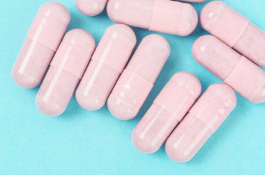Mavi arka planda Pembe kapsül hapları.