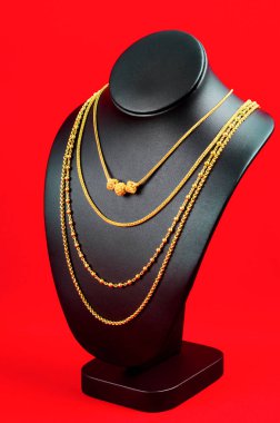 Kolye standı kırmızı kadife kumaşın üzerinde altın kolyeyle