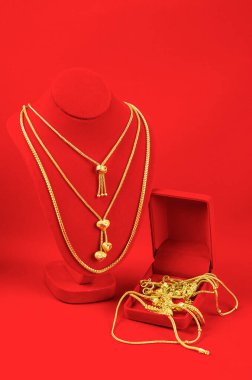 Kolye standı kırmızı kadife kumaşın üzerinde altın kolyeyle.