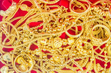 Kırmızı arka planda kırmızı kadife bir kutuda bir sürü altın kolye.