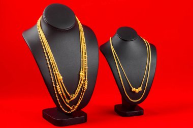 Kolye standı kırmızı kadife kumaşın üzerinde altın kolyeyle