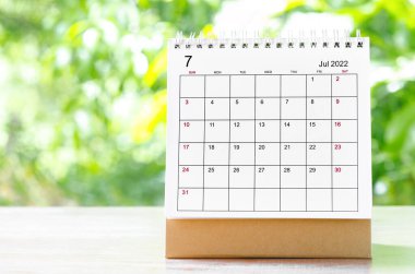 Organizatörün, doğanın arka planındaki ahşap masa üzerinde planlaması ve hatırlatması için Temmuz 2022 takvim masası..