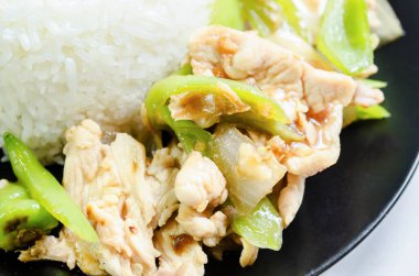 Tavuk, yeşil biberle kızartılmış ve siyah tabakta pilav buğulanmış. Tayland yemeği tarzı..