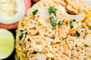 Kızarmış pirinç ve sebzeler masa örtüsünün üzerinde siyah tabakta. Tayland yemeği tarzı..